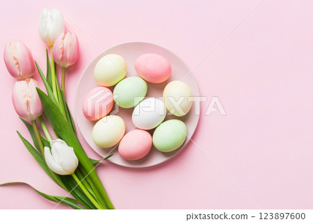 Happy Easter composition. Easter eggs in basket on colored table with yellow Tulips. Natural dyed colorful eggs background top view with copy space Happy Easter composition. Easter eggs in basket on colored table with yellow Tulips. Natural dyed colorful eggs background top view with copy space 123897600