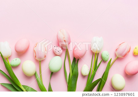 Happy Easter composition. Easter eggs on colored table with yellow Tulips. Natural dyed colorful eggs background top view with copy space 123897601
