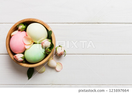 Happy Easter. Easter eggs in basket on colored table with yellow roses. Natural dyed colorful eggs background top view with copy space 123897664