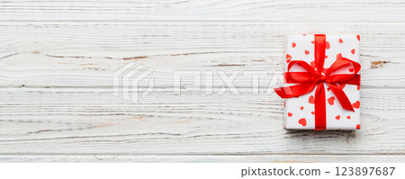 Valentine day composition: red gift box with bow and heart. Christmas present. View from above. Space for text. Holday greeting card Valentine day composition: red gift box with bow and heart. Christmas present. View from above. Space for text. Holday greeting card 123897687