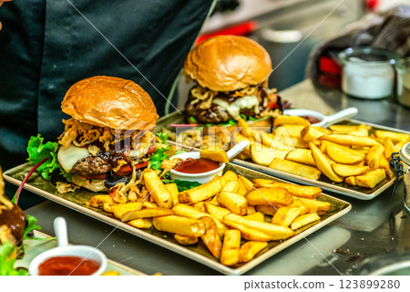 Home made hamburger with lettuce, cheese, beef meat and french fries placed on stainless steel table 123899280