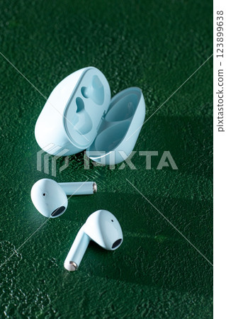 Wireless headphones on green background. Wireless, headphone in charging box. Wireless headphones on green background. Wireless, headphone in charging box. 123899638