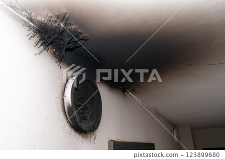 Burnt out LED lamp. A lampshade lamp on the wall after a fire. Spontaneous combustion and fire in a residential building. 123899680