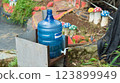 Outdoor water dispenser with plastic bottle in a garden setting view 123899949