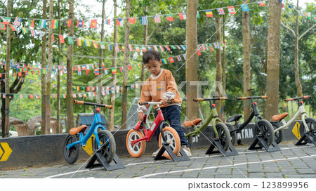 Young boy choosing balance bike in outdoor park setting for children 123899956