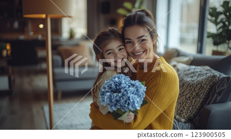 Smiling mother and daughter hugging with flowers indoor lifestyle Smiling mother and daughter hugging with flowers indoor lifestyle 123900505