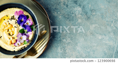 Gourmet Hummus with Edible Flowers and Pine Nuts on Blue Background Gourmet Hummus with Edible Flowers and Pine Nuts on Blue Background 123900698