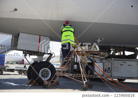 Refueling the plane at the airport. Male worker on the stairs. Refueling the plane at the airport. Male worker on the stairs. 123900816
