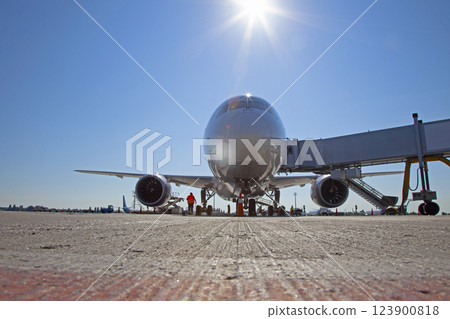 Boarding passengers on the plane through the boarding bridge. The plane lands at the international airport. Loading luggage. White airplane. Terminal Runway Boarding passengers on the plane through the boarding bridge. The plane lands at the international airport. Loading luggage. White airplane. Terminal Runway 123900818