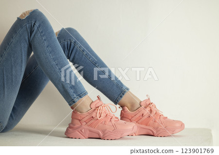 detail of sitting woman wearing pink trainers and jeans 123901769