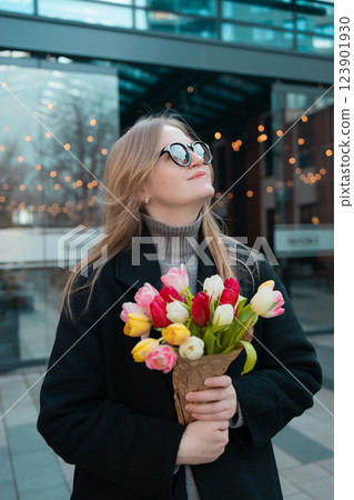 Happy International Women's Day Concept. Beautiful happy Caucasian woman smelling bunch of tulips with closed eyes 123901930