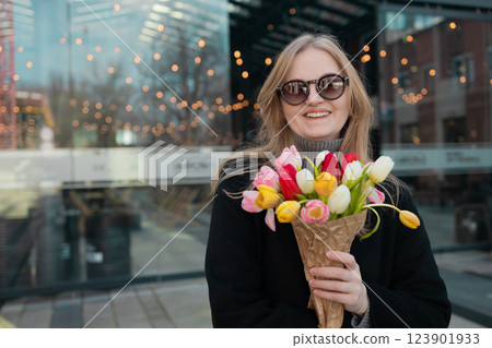 Happy International Women's Day Concept. Beautiful happy Caucasian woman smelling bunch of tulips with closed eyes 123901933