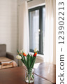 Bouquet of beautiful fresh tulips in a glass vase on wooden table in cozy modern interior. Spring flowers in glass vase at home. 123902213