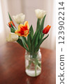 Bouquet of beautiful fresh tulips in a glass vase on wooden table in cozy modern interior. Spring flowers in glass vase at home. 123902214