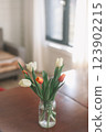 Bouquet of beautiful fresh tulips in a glass vase on wooden table in cozy modern interior. Spring flowers in glass vase at home. 123902215