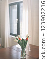 Bouquet of beautiful fresh tulips in a glass vase on wooden table in cozy modern interior. Spring flowers in glass vase at home. 123902216