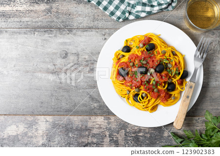 Italian Pasta puttanesca with tomato sauce, capers, and black olives on wooden table Italian Pasta puttanesca with tomato sauce, capers, and black olives on wooden table 123902383