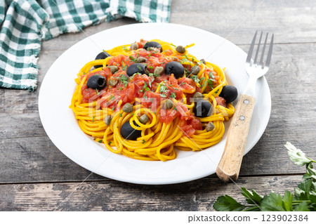 Italian Pasta puttanesca with tomato sauce, capers, and black olives on wooden table Italian Pasta puttanesca with tomato sauce, capers, and black olives on wooden table 123902384
