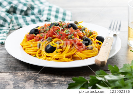 Italian Pasta puttanesca with tomato sauce, capers, and black olives on wooden table Italian Pasta puttanesca with tomato sauce, capers, and black olives on wooden table 123902386