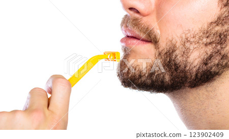 Young man with beard holding razor blade Young man with beard holding razor blade 123902409