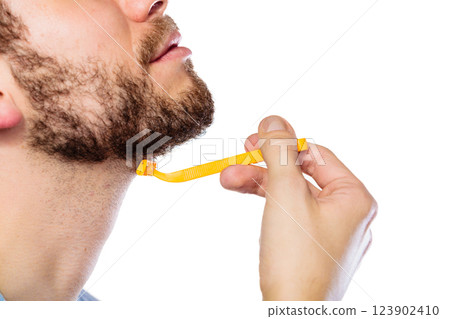 Young man with beard holding razor blade Young man with beard holding razor blade 123902410