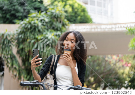 Coffee and Connection. Young woman enjoying her coffee while taking a selfie outdoors. 123902843
