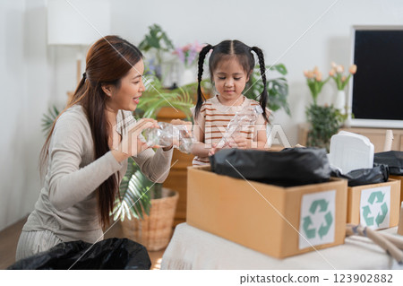 Eco-friendly Practices and Learning Together. A mother and daughter sorting recyclable materials in their living room. 123902882