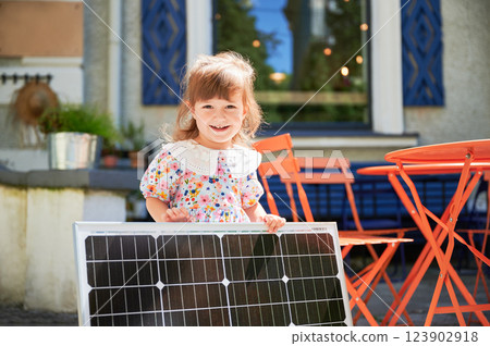 Lovely girl holding solar battery and smiling to camera. Learning about saving environment from childhood. Little steps to alternative lifestyle. 123902918