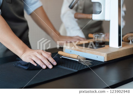 Entrepreneurship and Barista Skills. A focused barista meticulously cleaning the counter in a trendy coffee shop environment. Entrepreneurship and Barista Skills. A focused barista meticulously cleaning the counter in a trendy coffee shop environment. 123902948