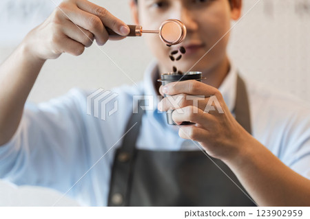 Precise Coffee Handling A barista measuring coffee beans with focus and skill. 123902959