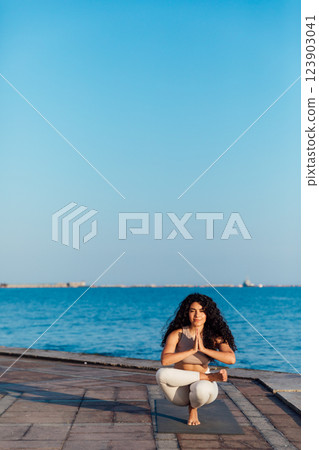 woman doing gymnastics yoga asana on the beach by the sea 123903041