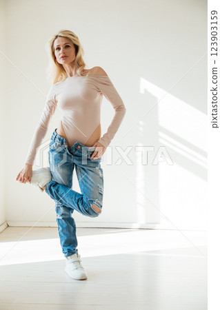 Beautiful fashion blonde woman in jeans by the window 123903159