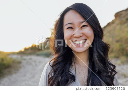 Young attractive Asian with long wavy hair outdoors. A charming Korean woman Young attractive Asian with long wavy hair outdoors. A charming Korean woman 123903520