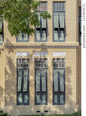 The Sunlight shines through Multiple green wooden louvered window shutters on cement wall. The Sunlight shines through Multiple green wooden louvered window shutters on cement wall. 123903672