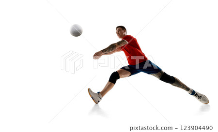 Low angle view of focused man, volleyball player in motion, hitting ball, playing against white studio background Low angle view of focused man, volleyball player in motion, hitting ball, playing against white studio background 123904490