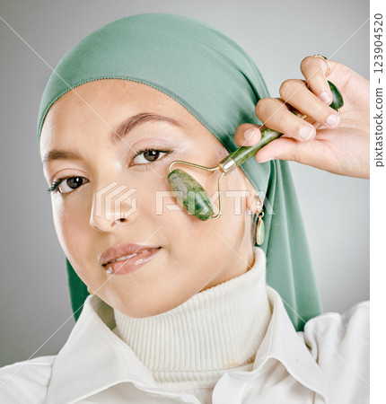 Muslim arab woman beauty, jade roller and facial skincare, cosmetics product and aesthetic wellness on studio background. Portrait islamic hijab, model face and green stone massage, self care or glow Muslim arab woman beauty, jade roller and facial skincare, cosmetics product and aesthetic wellness on studio background. Portrait islamic hijab, model face and green stone massage, self care or glow 123904520