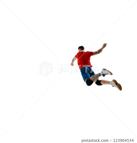 Back view image of determined athlete, male volleyball player dressed in red jersey and blue shorts, playing against white studio background 123904534