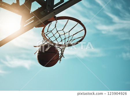 Below, basketball and net with sky in summer for shooting, scoring and points to win game. Hoop, rim and ball in closeup at basketball court for sports, competition or workout at playground, outdoor 123904926