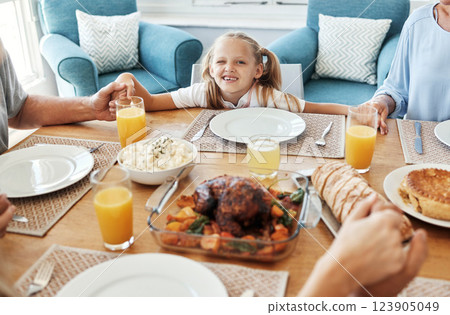 Food, family and praying with girl at a table, holding hands in gratitude, prayer and bonding before eating. Worship, pray time and child looking curious, hungry and playful while looking at a meal 123905049