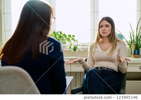 Sad unhappy young woman at therapy with female professional psychologist Sad unhappy young woman at therapy with female professional psychologist 123905146