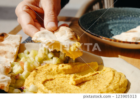 man dipping some naan bread on hummus man dipping some naan bread on hummus 123905313