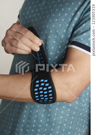man adjusts his epicondylitis bracelet man adjusts his epicondylitis bracelet 123905319