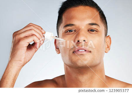 Man beauty, face and health serum oil for glowing, healthy and aesthetic skincare on grey studio background. Portrait young latino model liquid cosmetics product for clean facial skin wellness Man beauty, face and health serum oil for glowing, healthy and aesthetic skincare on grey studio background. Portrait young latino model liquid cosmetics product for clean facial skin wellness 123905377
