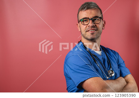 Smiling male healthcare professional in scrubs against a colorful background Smiling male healthcare professional in scrubs against a colorful background 123905390