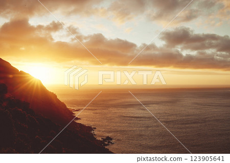 Sunset, sea and clouds with a view of the beautiful ocean or horizon during summer outdoor. Water, nature and sunrise with a picturesque scene of the earth, mountain or cloudy skin outside in the day 123905641
