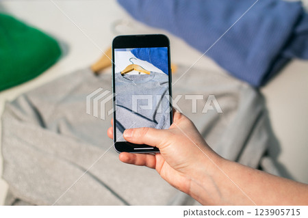 Woman taking photo of used clothes in good quality. Preparing to sell in second hand online market. Second hand and resale concept. Clothes donation. 123905715