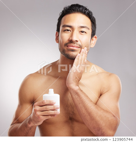 Beauty, lotion and portrait of man in studio to apply cream for cosmetics or dermatology. Aesthetic, moisturizer and skincare with shirtless model on gray background for cosmetology or satisfaction Beauty, lotion and portrait of man in studio to apply cream for cosmetics or dermatology. Aesthetic, moisturizer and skincare with shirtless model on gray background for cosmetology or satisfaction 123905744