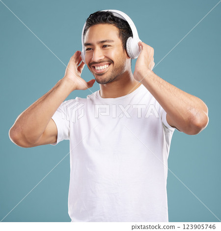 Studio, man and happy with headphones for music, podcast and satisfied with playlist for motivation. Smile, male person and model for listening to audio, streaming sound and radio by blue background 123905746