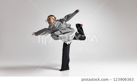 Confident woman in business attire balancing on one leg, arms stretched, playful motion against white background. Confident woman in business attire balancing on one leg, arms stretched, playful motion against white background. 123906363