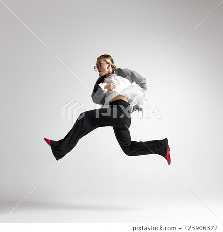 Graceful leap of woman in classic black and white attire against white background, as she hurry up. Dynamic leadership. Graceful leap of woman in classic black and white attire against white background, as she hurry up. Dynamic leadership. 123906372